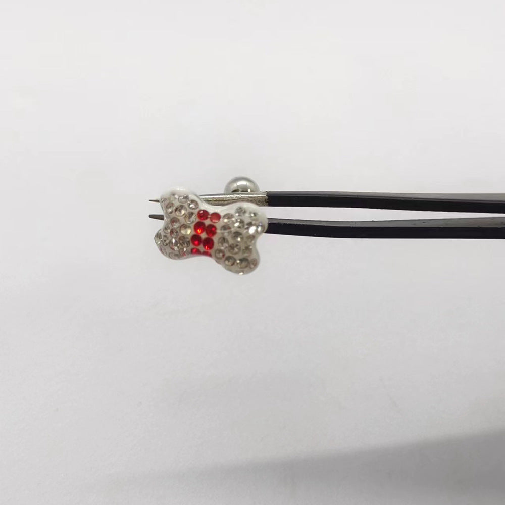 One White butterfly tongue barbell held with tweezers, featuring clear rhinestones around a red center.