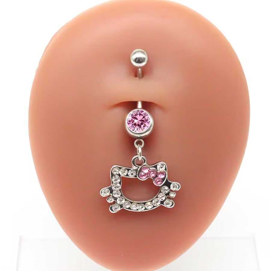 Real life dangle effect of a pink crystal kitten navel ring showcased on a silicone belly piercing display model for standard fit reference.