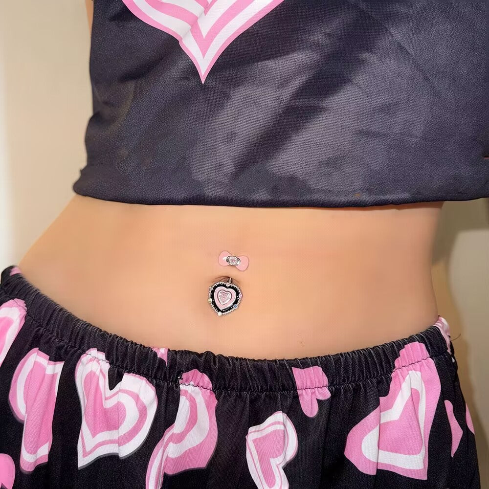 On-body model wearing the pink bow heart belly button ring paired with Y2K low-rise pants for coquette aesthetic fashion inspiration.
