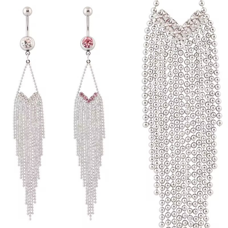 Two dangling tassel belly button rings side by side, one with clear white crystals and one with rose pink crystals, showcasing long silver ball chain fringes.