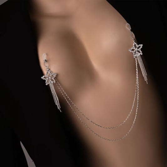A close-up of a model wearing an integrated silver non-piercing nipple clasp chain set with rhinestone star charms and double-layer tassels under a black blazer.